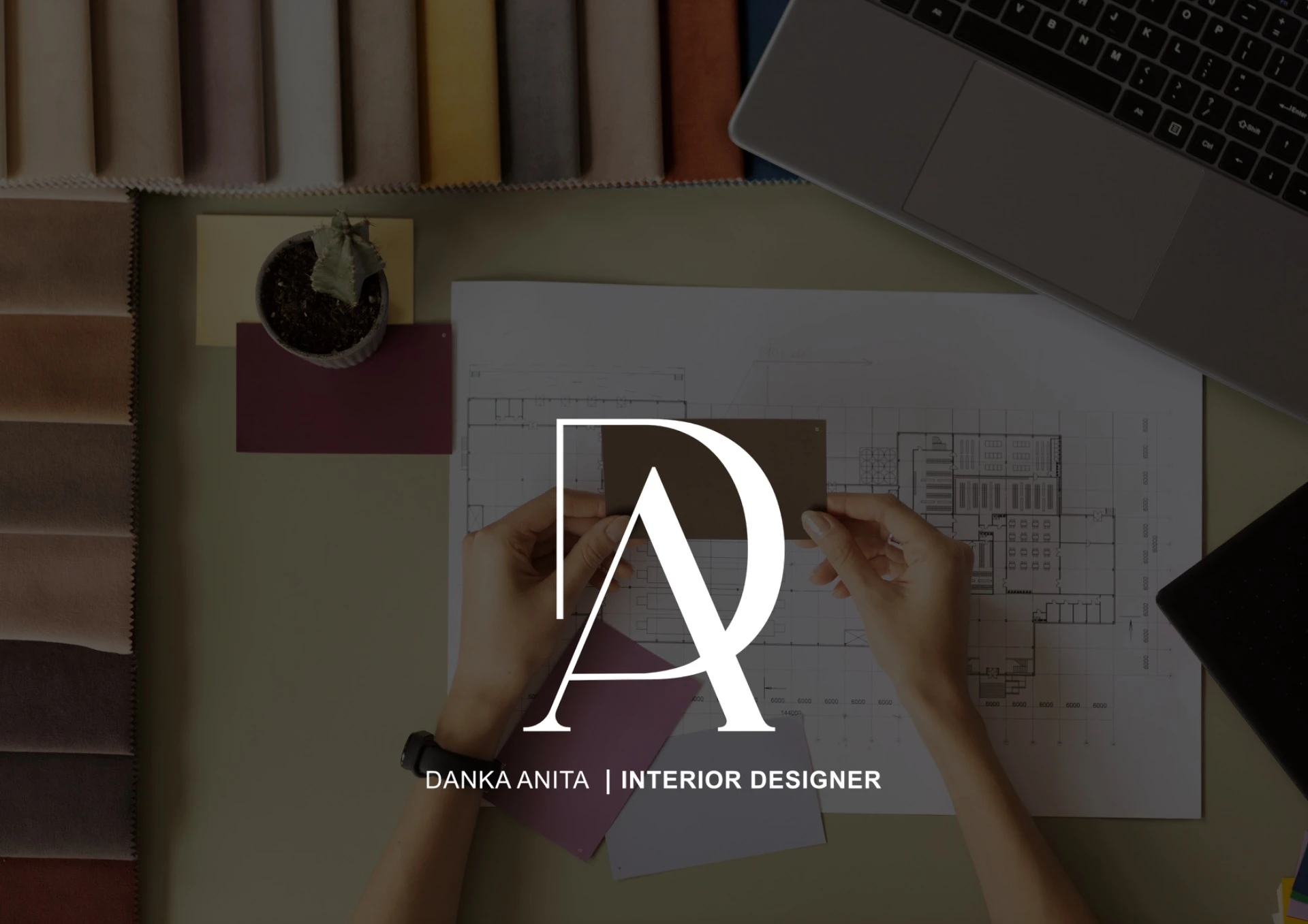 Tervrajzok és a DA logó egy interior design íróasztalon